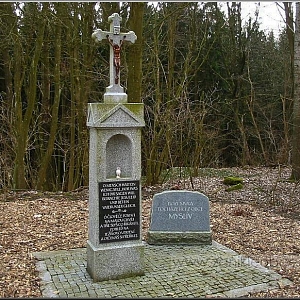 Pietní křížek zaniklé vsi Myslív/Schneiderhof stojící za kostelem v prostoru zaniklé fary a školy.